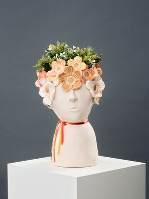un vase blanc contenant des fleurs en forme de tête