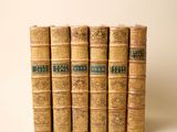 six vieux livres alignés sur une surface blanche