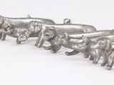 three silver elephants that are on a white surface