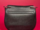 a black leather purse with two metal handles on a red background