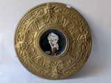 a gold plate with a picture of a woman in a hat