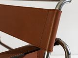 a brown leather chair with a metal frame on a white surface