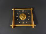 a gold clock on a black table with a black background