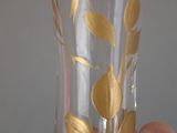 a person holding a glass with gold leaves on it