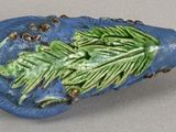 a blue vase with a green leaf decoration on it