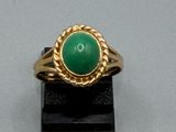 une image d'une bague en or avec une pierre verte au centre