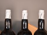 three bottles of wine sit in a wooden crate with a knife