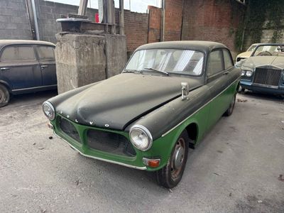 an old green car parked in a parking lot