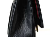 black leather purse with gold chain strap on white background