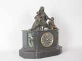 une statue représentant une femme et deux enfants assis sur une horloge