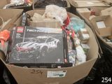 une boîte remplie de jouets et d'autres objets posée par terre