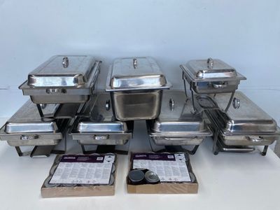 a lot of silver trays with lids on a table