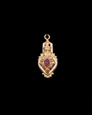 un pendentif en or orné d'une pierre rouge au centre
