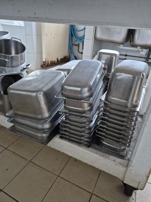 Plusieurs plateaux de nourriture sont empilés sur un chariot dans une cuisine