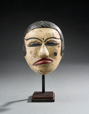 une image représentant un masque en bois posé sur un socle, sur fond noir
