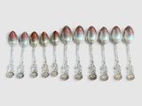 six cuillères en argent sont alignées sur une surface blanche