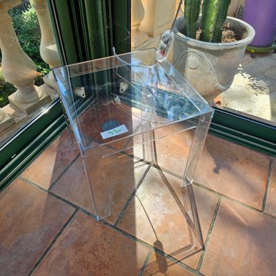 une table claire avec un plateau en verre, posée sur un sol carrelé
