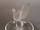 a glass bird that is sitting on a glass plate