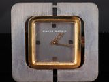 a silver and gold clock sitting on top of a black table