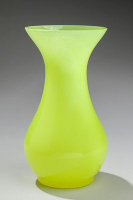 un vase en verre jaune posé sur une surface blanche