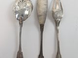 trois cuillères et une fourchette en argent sur une surface blanche