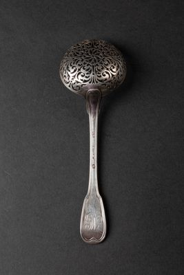 silver spoon on a black background with a pattern on the handle