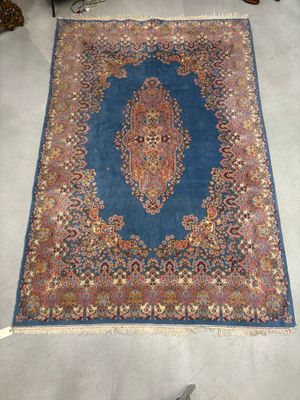 une photo d'un tapis bleu et rouge posé sur un sol blanc