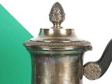 a silver coffee pot sitting on a table with a green and white background