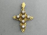un pendentif en forme de croix en or et diamants sur un fond gris