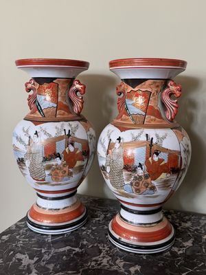 une paire de vases asiatiques posés sur une table, avec un mur en arrière-plan
