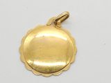 a close up of a gold plated pendant on a white surface