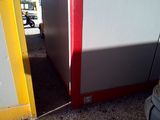 a small red and white refrigerator in the corner of a room