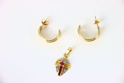 deux paires de boucles d'oreilles et un pendentif posés sur une surface blanche