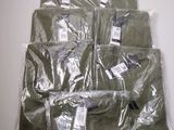 une pile de t-shirts verts emballés dans du plastique, posée sur une table