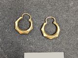deux paires de boucles d'oreilles créoles en or posées sur une surface noire