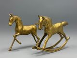 une paire de chevaux à bascule anciens en laiton sur fond gris