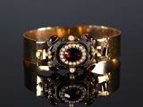 a close up of a gold bracelet with garnets and pearls