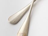two spoons and a fork on a white surface