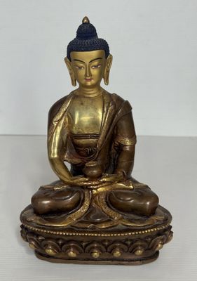 statue en laiton représentant une personne assise en position du lotus sur une surface blanche