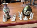 de nombreuses figurines posées sur une table, avec un vase en arrière-plan