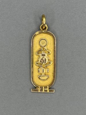 a gold plated pendant with an egyptian symbol on it