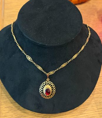 a black hat with a gold chain and a red stone pendant