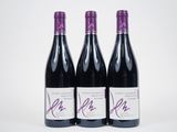 trois bouteilles de vin sont posées sur une surface blanche