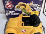 yellow toy car with black roof and door open in front of a box of ghostbus