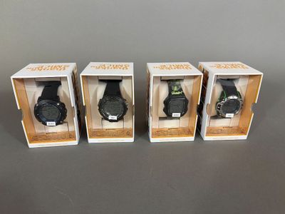 trois montres dans leurs boîtes, posées sur une table avec un fond gris