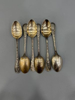six spoons are lined up in a row on a gray surface
