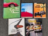 trois livres posés sur une table, avec une voiture rouge et une voiture jaune