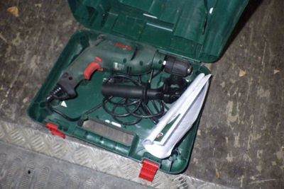 une mallette verte posée par terre, contenant des outils