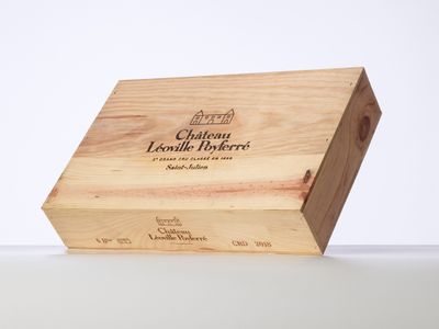 La boîte en bois contient une bouteille de vin posée sur une surface blanche.