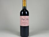 a bottle of red wine sitting on top of a white table